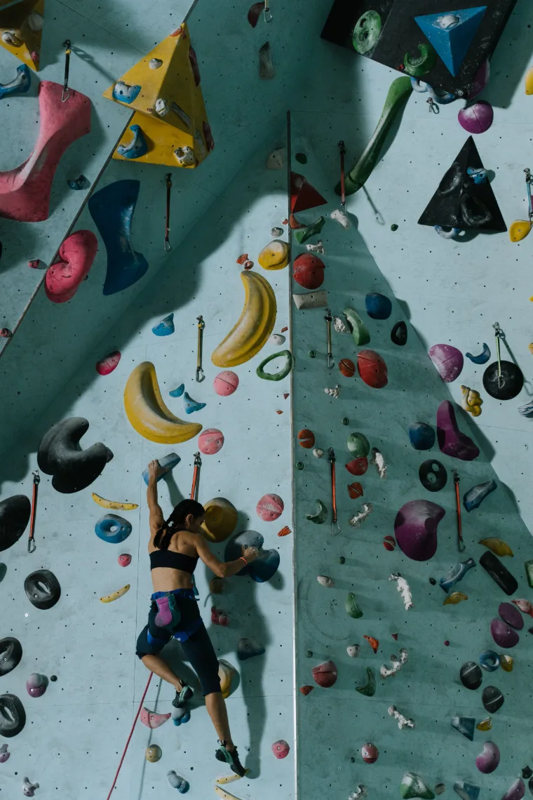 A climber chalking up below an indoor boulder problem